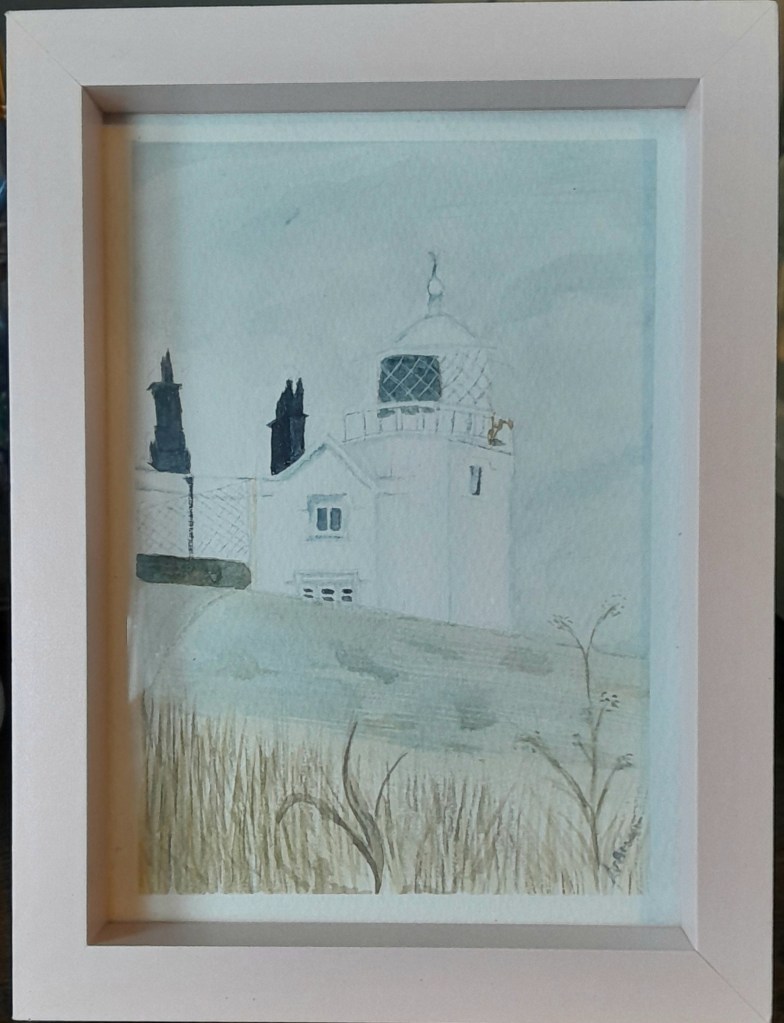 Framed watercolour painting of a lighthouse and house seen through tall grasses