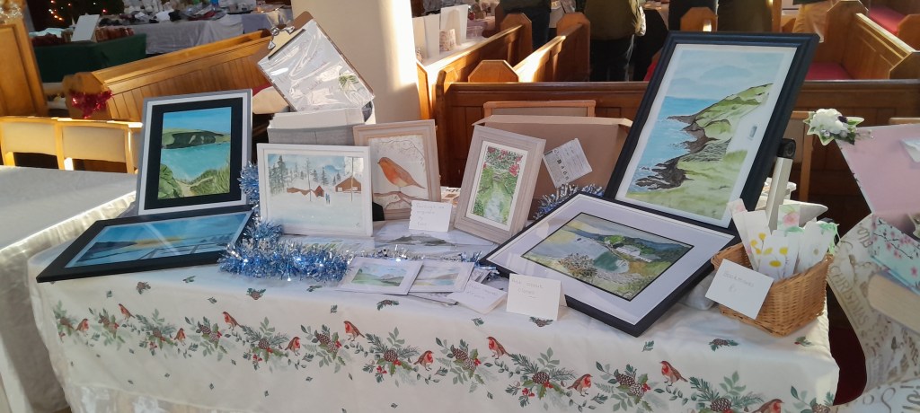 Display of framed watercolour paintings on a table at a craft fair
